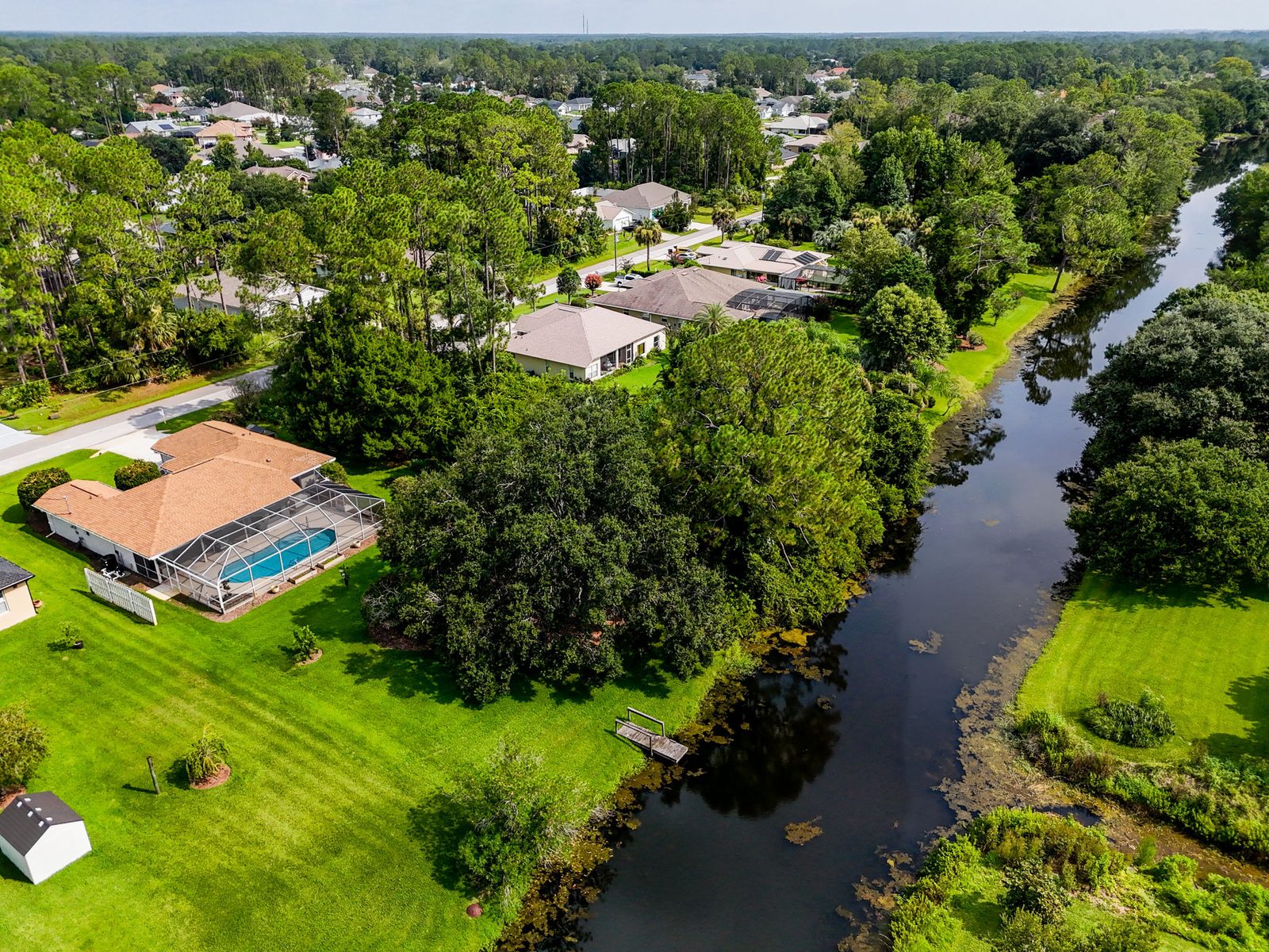 Aerial view of 62 Bayside Dr with pool and freshwater canal behind the property